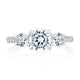 Top view of a 14K white gold three-stone engagement ring with a round center diamond